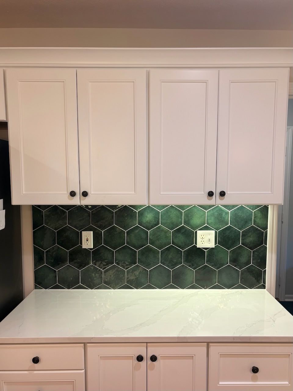 Kitchen with painted white cabinets and green tile backsplash